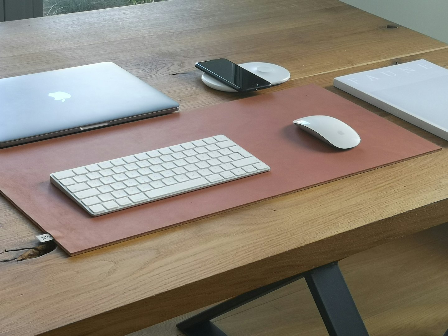 Electronic devices and a book arranged on a wooden desk.